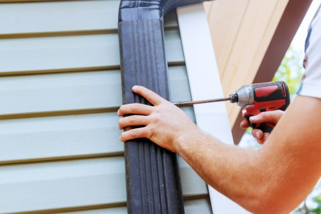 Installation rain gutters on a roof with installation of downpipes downspout bends